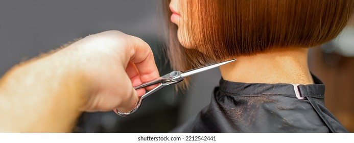 Woman Having A New Haircut. Male Hairstylist Cutting Brown Hair With Scissors In A Hair Salon