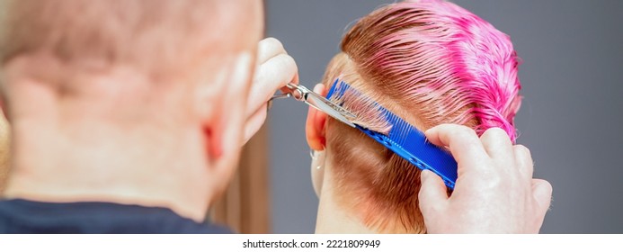 Woman Having A New Haircut. Male Hairstylist Cutting Pink Short Hair With Scissors In A Hair Salon