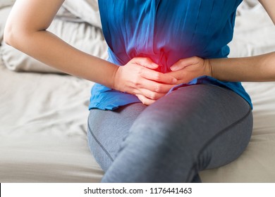 Woman having painful stomach ache at home,Female suffering from abdominal pain,Period cramps,Hands squeezing belly,Stomach pain,Menstrual cramps,Pelvic bone,Dysmenorrhea