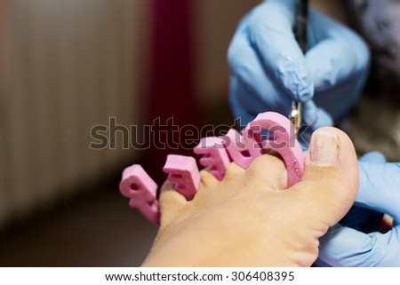 Woman having a professional pedicure treatmant, and puting gel on fingertoes