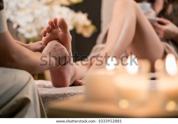 Woman having reflexology foot massage in wellness\
spa center