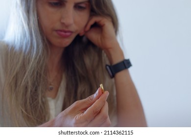 Woman Having Second Thoughts About Her Marriage Holding And Looking At Her Wedding Ring.