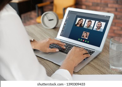 Woman having video chat with colleagues at table in office, closeup