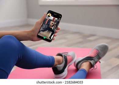 Woman Having Workout With Personal Trainer Via Smartphone At Home, Closeup