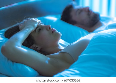 The woman with a headache lay near the man in the bed. night time - Shutterstock ID 674033656