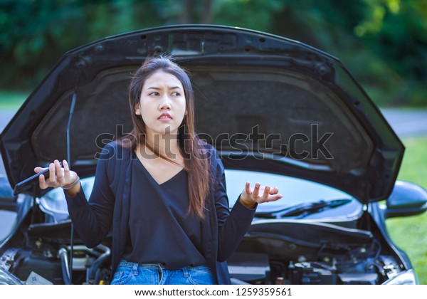 woman\
headache while looking at broken down car on\
road.
