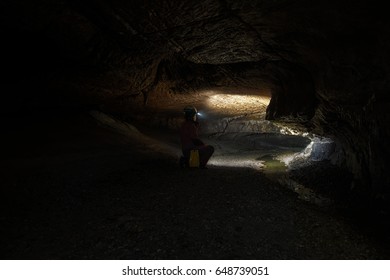 Woman With Headlamp Inside Cave