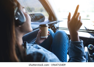 A Woman With Headphone Enjoy Listening To Music And Drinking Coffee While Riding In The Car