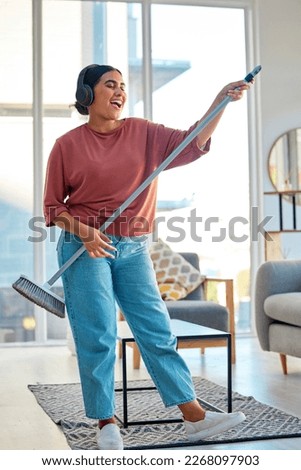 Woman, headphones and cleaning living room with music for home spring cleaning, housekeeping or sweeping floor. Singing karaoke, online podcast and happy cleaner or housework with broom in apartment