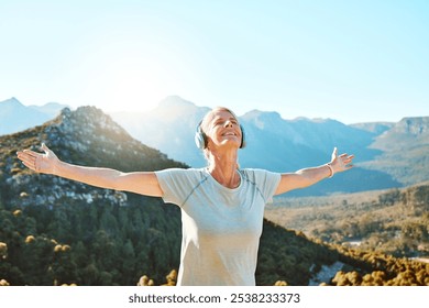 Woman, headphones or freedom on mountain outdoor for fitness achievement, exercise victory or workout goals. Mature, person and happy with hands raised on hill for training success with mockup space - Powered by Shutterstock