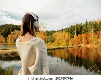 Frau mit Kopfhörern in der Nähe des Sees im Herbst