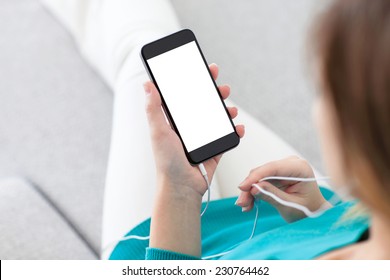 woman with headphones sitting on a sofa and holding a phone with isolated screen