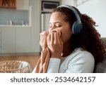 Woman, headphones and smell laundry in home, clean scent and listening to music in apartment. Female person, washing and inhale aroma of clothes or fresh cotton, cleaner and hearing sound or audio