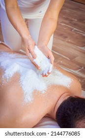 A Woman Healer Performs A Ritual With Salt, Pours Salt On The Back Of A Lying Man. Relaxation.