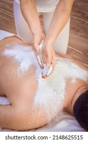 A Woman Healer Performs A Ritual With Salt, Pours Salt On The Back Of A Lying Man. Relaxation.