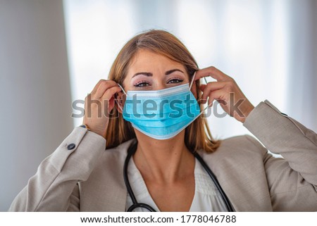 Woman healthcare professional demonstrating proper donning of mask for protection from coronavirus. Up close female healthcare worker putting on safety equipment 