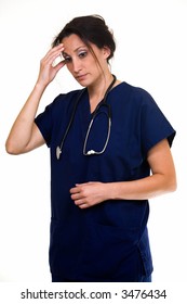 Woman Healthcare Worker Wearing Dark Blue Scrubs With Stethoscope Around Shoulders With Touching Forehead Demonstrating Having A Headache Standing On White