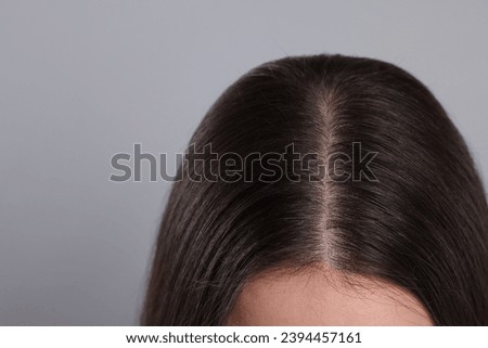 Woman with healthy hair on grey background, closeup. Space for text