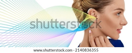 Woman with hearing aid behind the ear with colorful sound waves showing variety of sounds going to the ear. Hearing solutions, concept