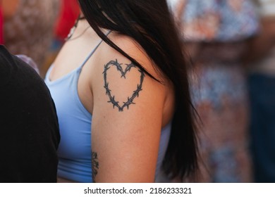 A Woman With A Heart Tattoo On A Shoulder Close-up. Heart Made Of Barbed Wire Tattoo. Diverse People At Pride March: VALENCIA, SPAIN - JUNE 25 2022