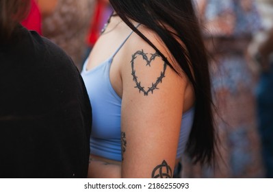 A Woman With A Heart Tattoo On A Shoulder Close-up. Heart Made Of Barbed Wire Tattoo. Diverse People At Pride March: VALENCIA, SPAIN - JUNE 25 2022