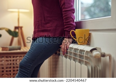 Woman heating on a chilly winter day, energy and gas crisis, cold room, heating problems.