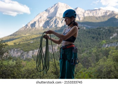 A woman in a helmet coils a rope against the background of a large mountain, a rock climber prepares equipment for climbing, safety equipment for rock climbing - Powered by Shutterstock