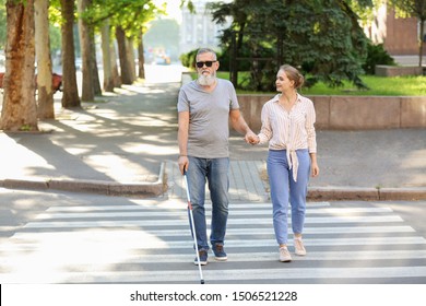 Woman Helping Blind Mature Man To Cross Road