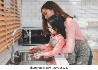 Woman Helping Daughter Wash Hands At Kitchen Sink. Happy Young Mother With Daughter Washing Hands With Liquid Soap In Kitchen After Messy Doing Bakery Decorating Birthday Cake Or Cooking.