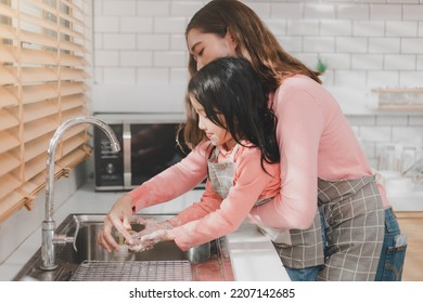 Woman Helping Daughter Wash Hands At Kitchen Sink. Happy Young Mother With Daughter Washing Hands With Liquid Soap In Kitchen After Messy Doing Bakery Decorating Birthday Cake Or Cooking.