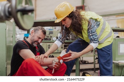 Woman is helping her colleague after accident in factory. First aid support on workplace concept. - Shutterstock ID 2164475229