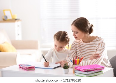 Woman helping her daughter with homework at table indoors - Shutterstock ID 1712796520
