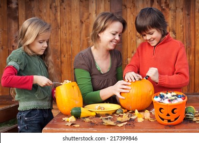 Woman helping kids to carve their pumpkin Halloween jack-o-lantern