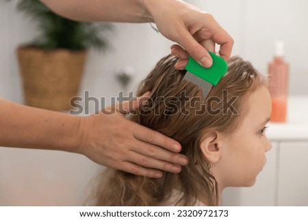 A woman helps to get rid of lice and parasites on the head of a little girl, combs her head with a special comb. Treatment of lice and nits. High quality 4k footage