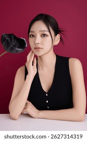 A woman in her 20s posing in front of black poppy flowers