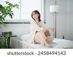 Woman in her 20s sitting on bed