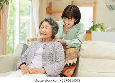 A woman in her 30s rubbing her grandmother's shoulder - Powered by Shutterstock