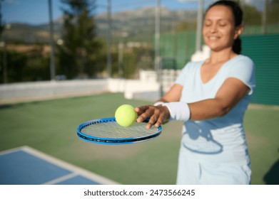 Woman in her 40s enjoys a game of tennis on an outdoor court. She is smiling and holding a tennis racket, capturing a moment of fun and fitness. - Powered by Shutterstock