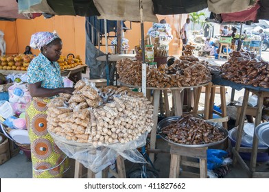 A Woman In Her 40s In A Traditional African Dress Selling Local Ivorian Sweets And Nuts At The Abidjan Market. Abidjan, Ivory Coast, Africa, Circa May 2013. Benin, Togo, Zambia, Gambia, Guinea, Mali