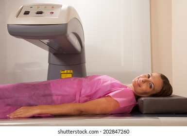 Woman In Her 40s Undergoing Scan At Bone Densitometer Machine.