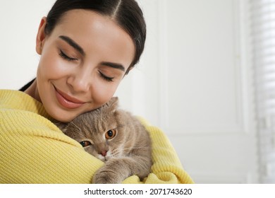 Woman with her adorable cat at home, space for text