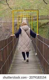 A Woman With Her Back Turned, Crosses The Suspension Bridge.