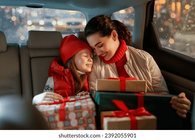 Woman and her child  holding presents and delivering them on car to home. Holidays concept. Time of Christmas Eve. 