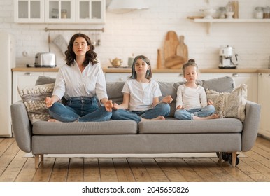 Woman and her children are meditating at home. - Shutterstock ID 2045650826