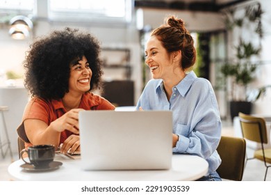 Woman and her client discuss business ideas and collaborate over coffee in a café. Happy business partners using a laptop as they engage with each other in a lunch meeting. - Powered by Shutterstock