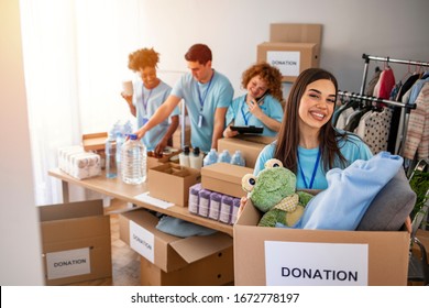 Woman And Her Colleague Working In Homeless Shelter. Cheerful Food Drive Manager. Happy Diverse Group Of Volunteers At Food Bank. Happy Woman Volunteers At A Food Bank 