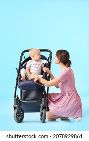 Woman And Her Cute Baby In Stroller On Color Background