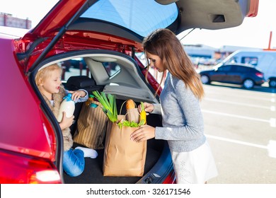 Woman And Her Daughter After Shopping In A Mall Or Shopping Centre And Driving Home Now With Her Car Outdoor