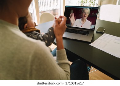 Woman with her daughter having video call with her mother. Woman connecting with her mother on a video call while at home. - Powered by Shutterstock