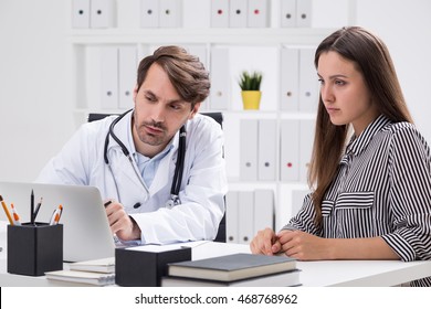 Woman and her doctor look at computer screen in office. Concept of modern medical care.